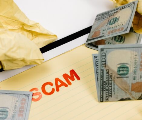 Scam written on paper covered with dollar bills